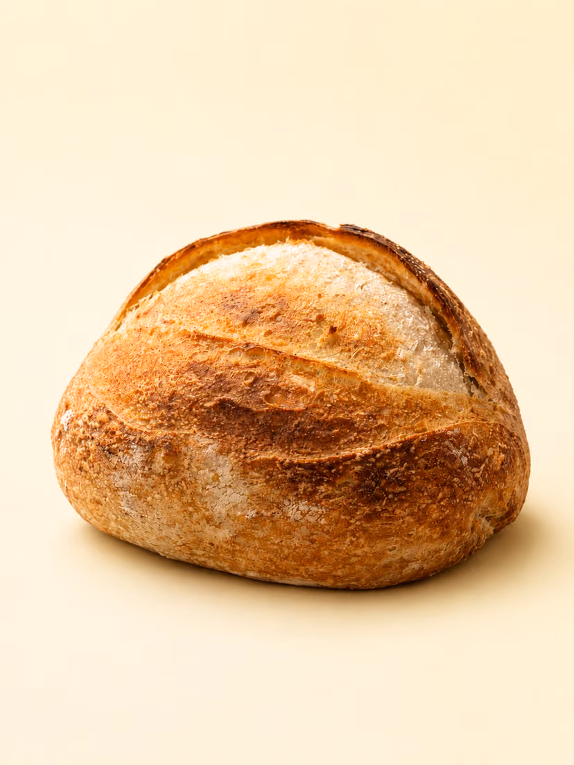 A dark crusted sourdough loaf cooling on a rack