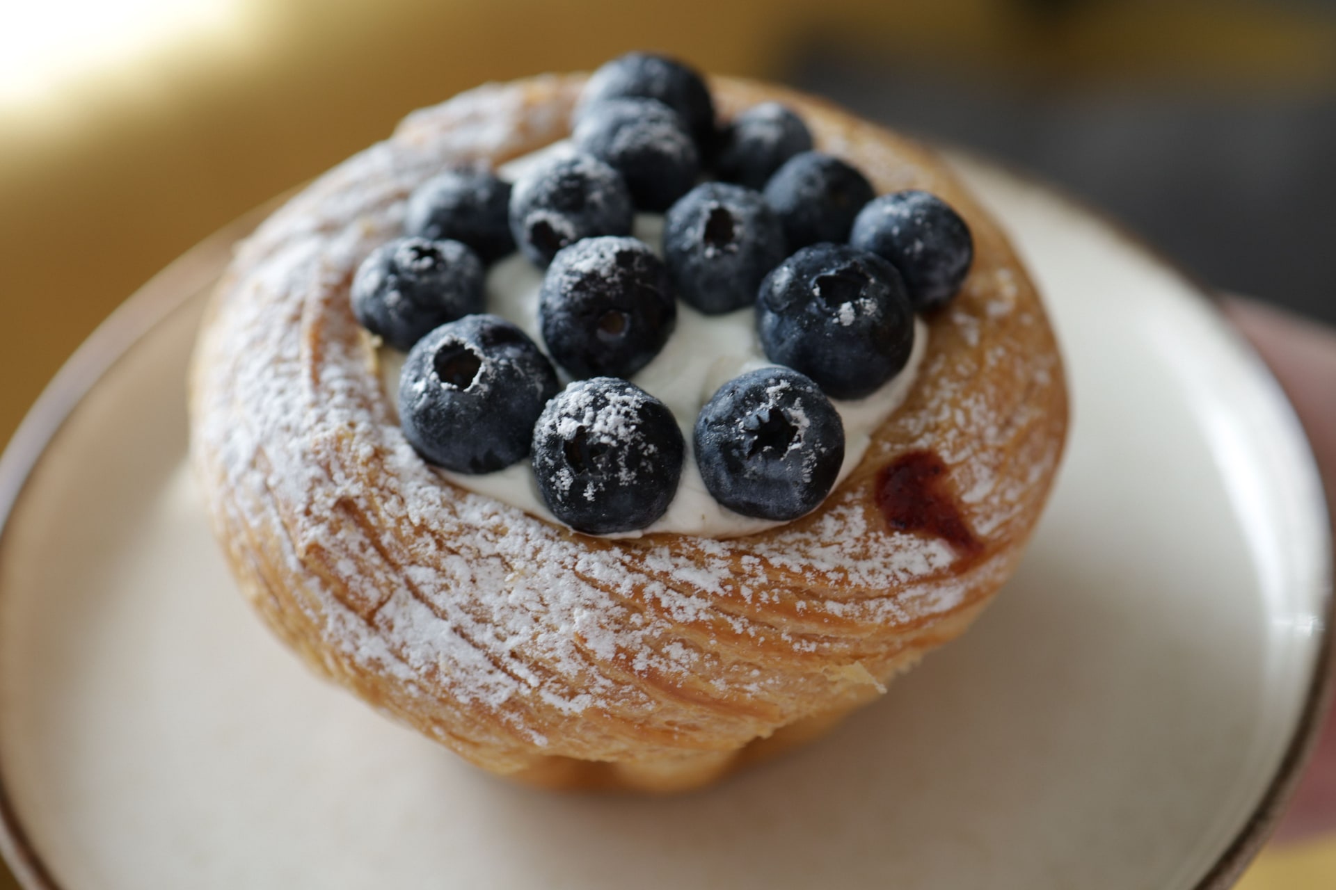 A blueberry streusel bun beside other berry pastries from the bakery