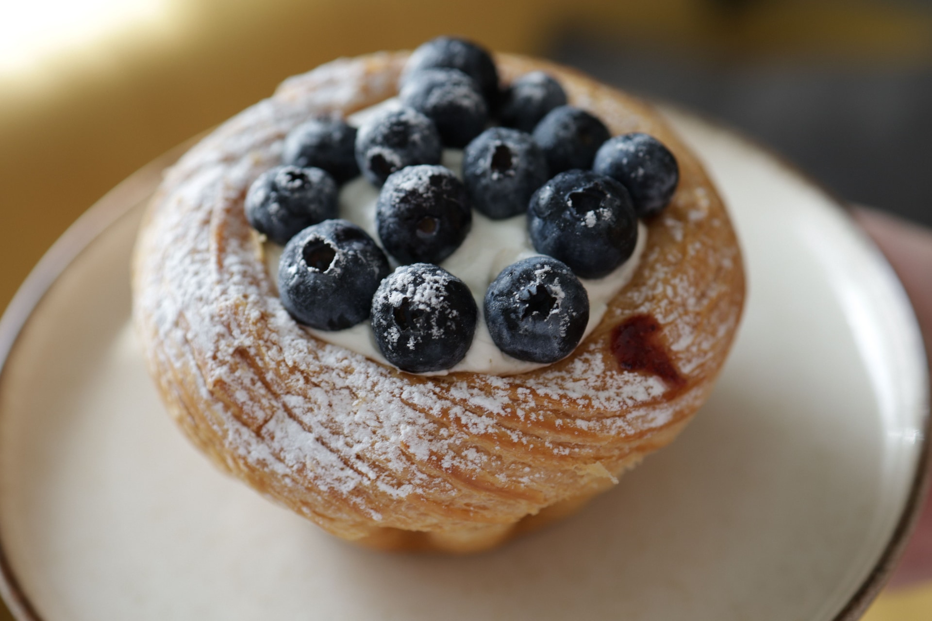 A blueberry streusel bun beside other berry pastries from the bakery
